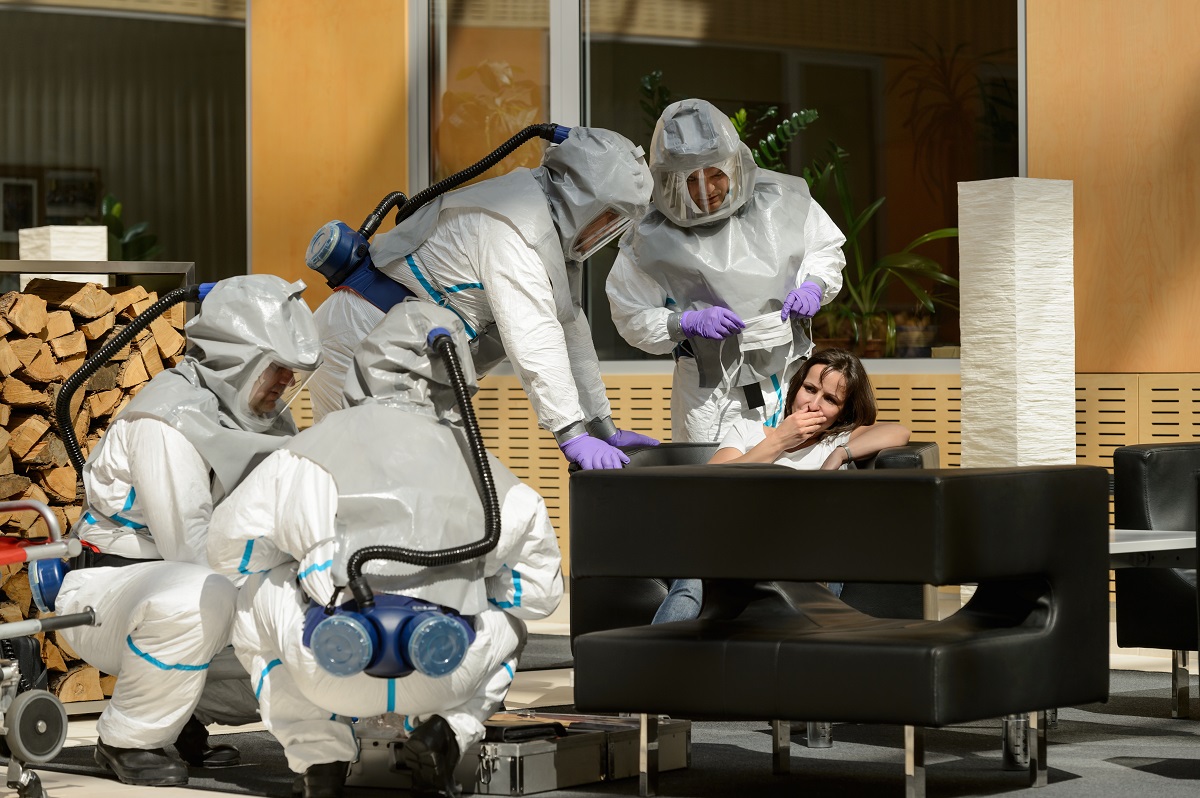 Biohazard medical team assisting contaminated female patient in lobby